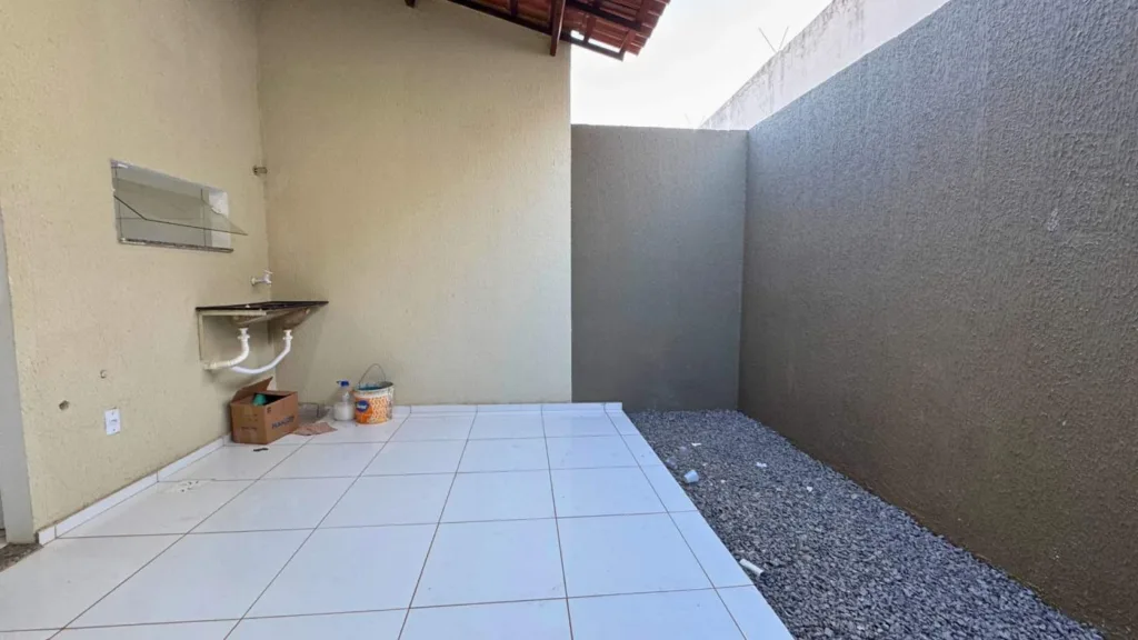 Área de serviço da casa em Campo Alegre com tanque, cobertura e faixa externa com brita