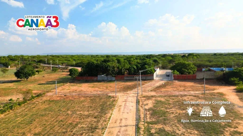 Vista aérea do acesso e dos terrenos do Canaã 3, com construções no entorno