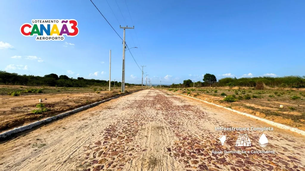 Vista da via com calçamento, postes e terrenos do Canaã 3