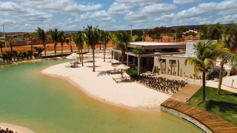 Vista da praia artificial, faixa de areia, palmeiras e espaço de convivência do Conviver Riviera