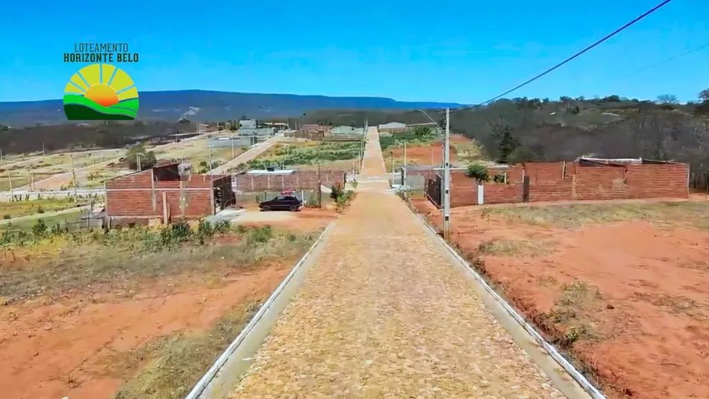 Rua pavimentada e terrenos do Horizonte Belo, com a serra ao fundo